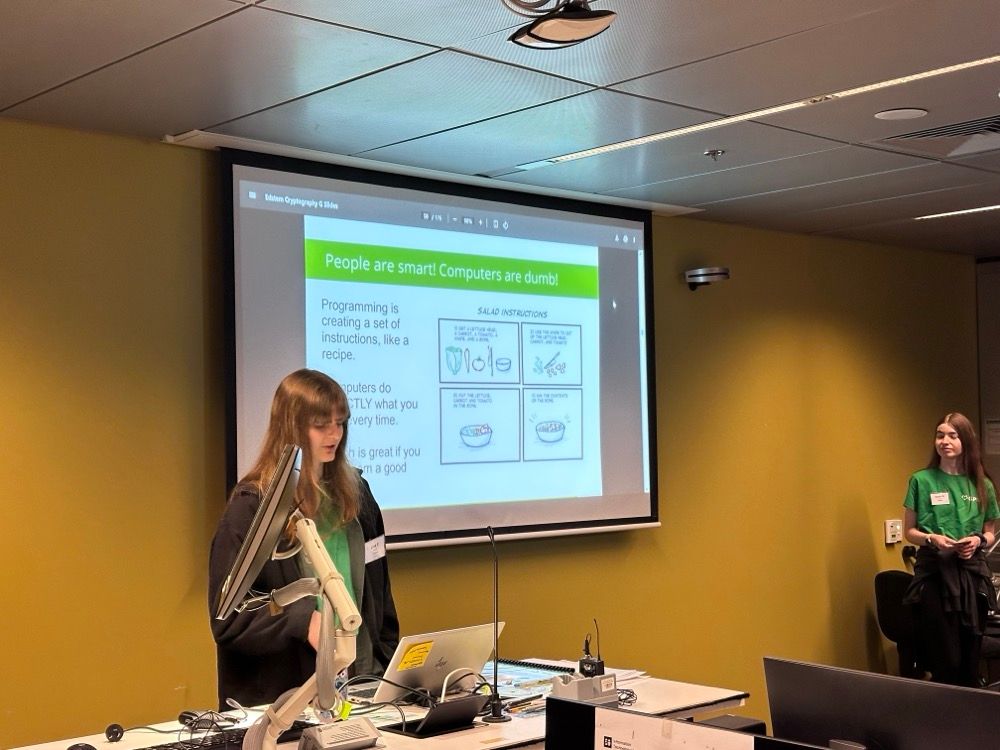 A woman giving a talk at a tech event with a slide that reads: "People are smart! Computers are dumb!"