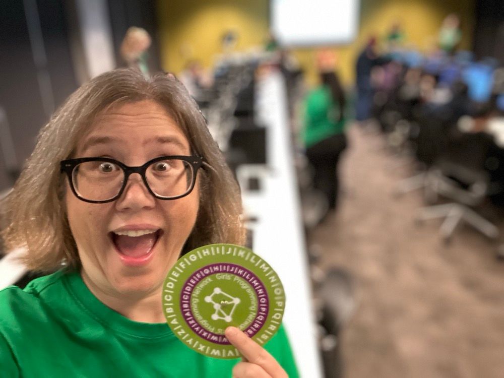 A smiling woman holding a green and purple paper wheel
