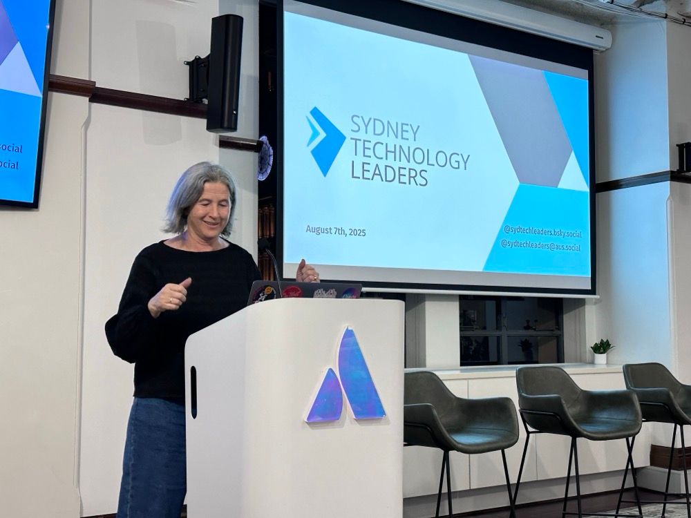 A woman presenting at a lectern in front of a slide that says Sydney Technology Leaders