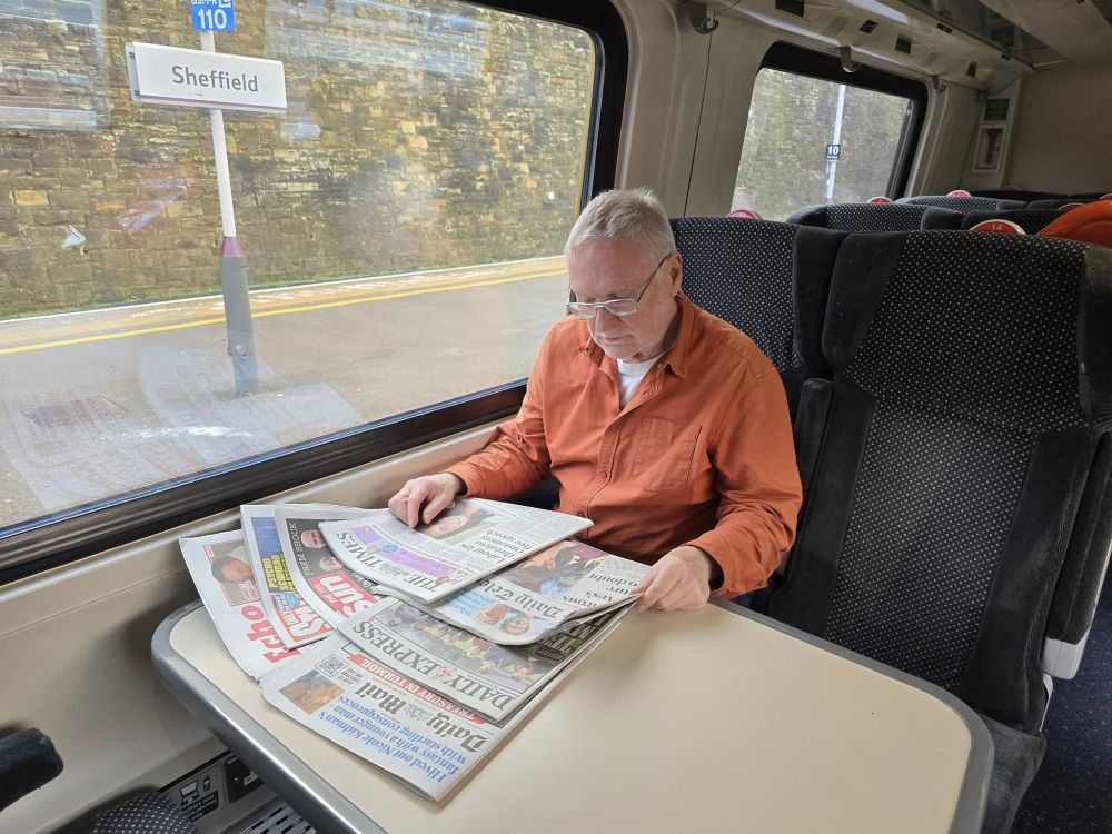 photo of Jon Fuller on a train reading the billionaire press