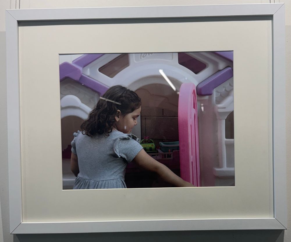 Framed photograph of a little girl entering a playhouse with a pink door