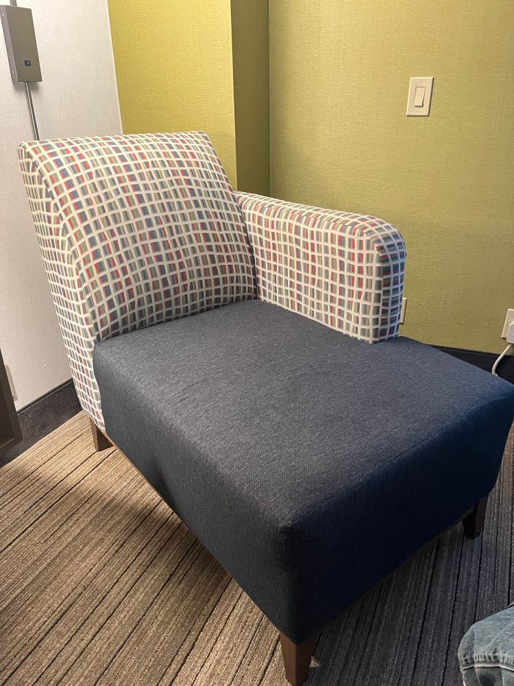 A couch in a hotel room next to the bed.