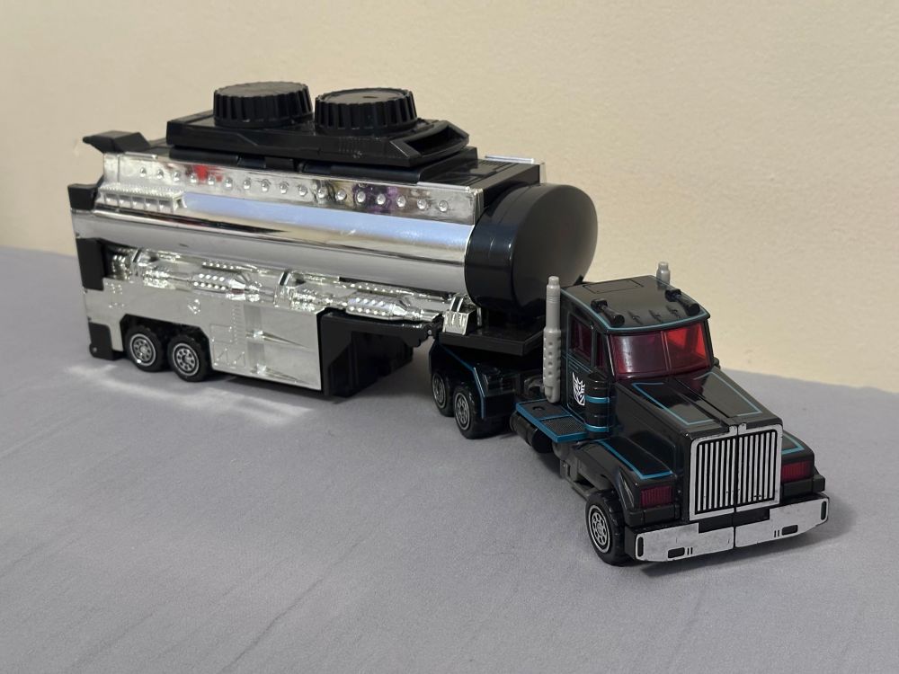 a black long-nosed truck towing a cylindrical trailer