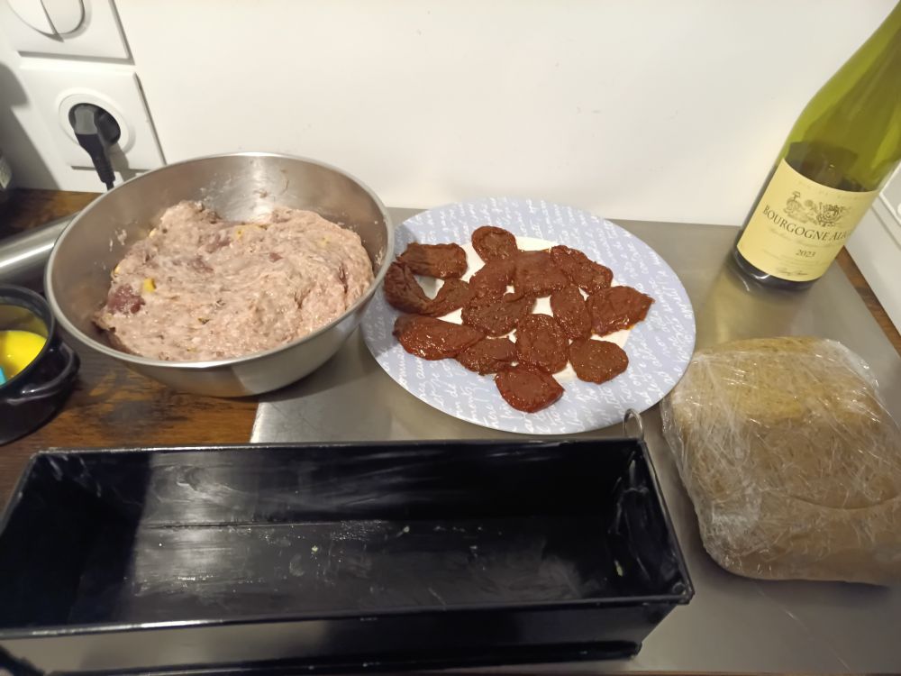 Le plat à pâté croûte, la pâte sortie du frigo, un cul de poule contenant la mêlée et un ramequin d'oeuf 