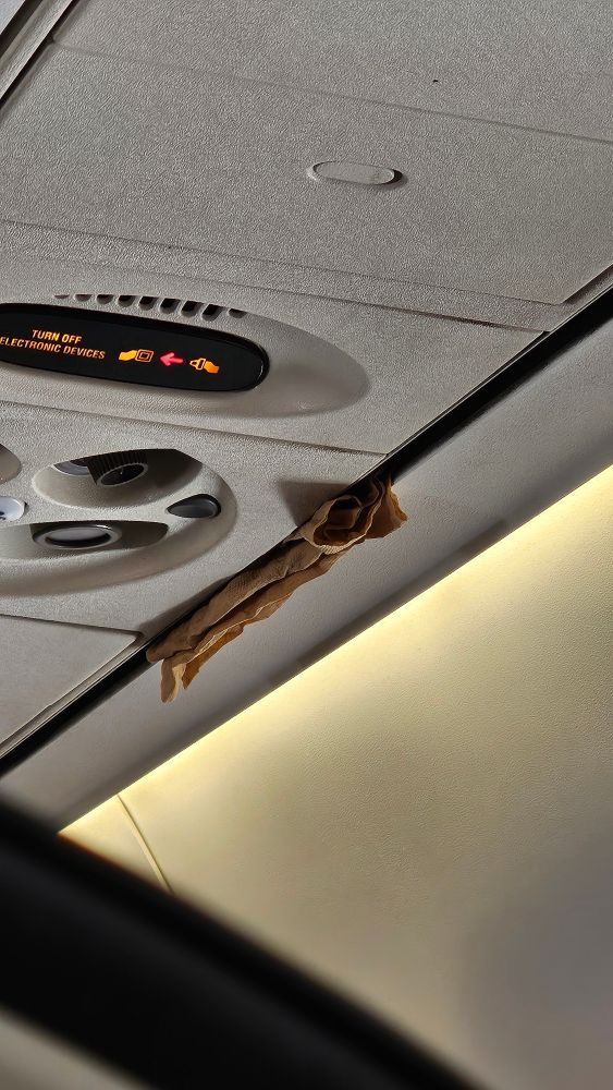 Napkins shoved in a crack by the AC panel on a plane.