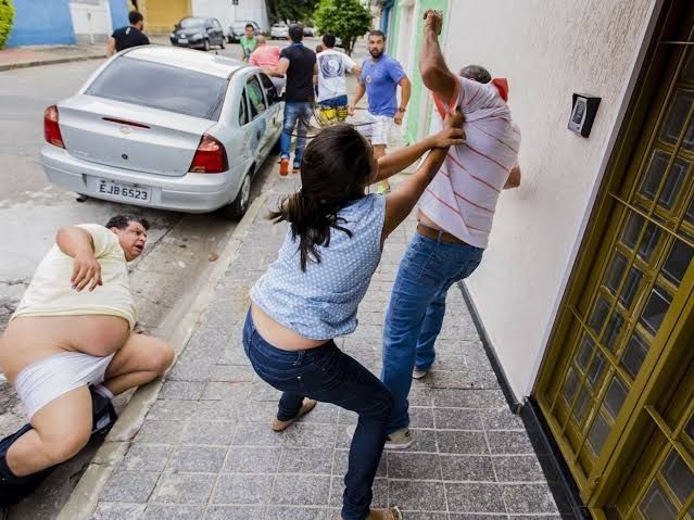 Foto de pancadaria tirada durante as prévias do PSDB Paulista em 2016, mostrando uma mulher agarrada à camisa de um homem que tenta se desvencilhar enquanto um segundo homem observa caído na sarjeta com as calças arriadas e a cueca na altura dos joelhos