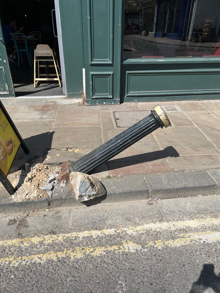 Bollard at precarious angle with remains of pavement around base