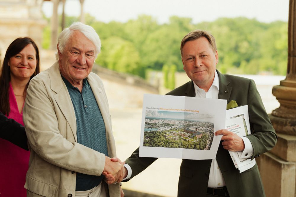 Zwei Personen im Vordergrund halten eine Planungsvisualisierung des neuen Campus auf dem Brauhausberg in Potsdam in die Kamera. Die Personen sind: Prof. Hasso Plattner, Stifter der Hasso Plattner Foundation und Prof. Oliver Günther, Präsident der UP. im Hintergrund ist eine Frau zu sehen, die Frau ist: Brandenburgs Wissenschaftsministerin Dr. Manja Schüle