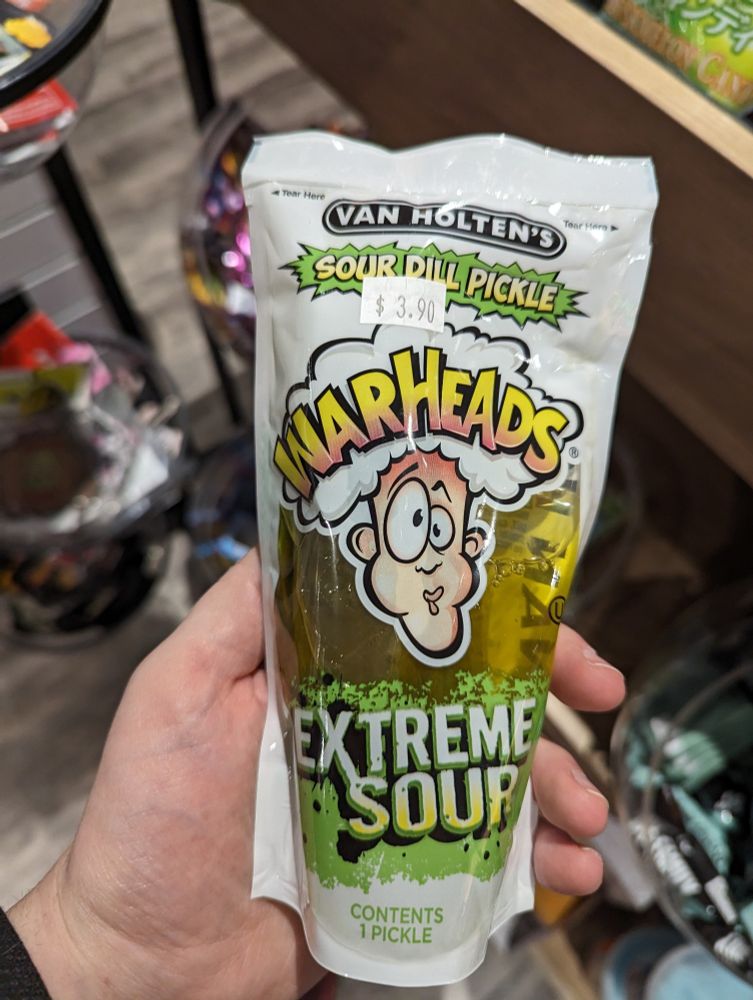 A single pickle in a bag. The bag says "Van Holten's Sour Dill Pickle WARHEADS EXTREME SOUR contents 1 pickle"