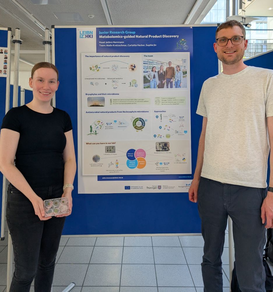 Two people standing in front of a scientific poster describing the research of our group.