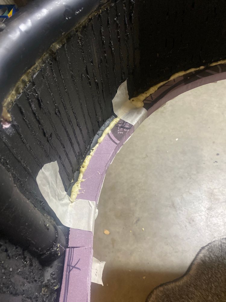 Picture of some pink foam with tape next to the black painted foam and pipes of the inside of the front nose of land speeder