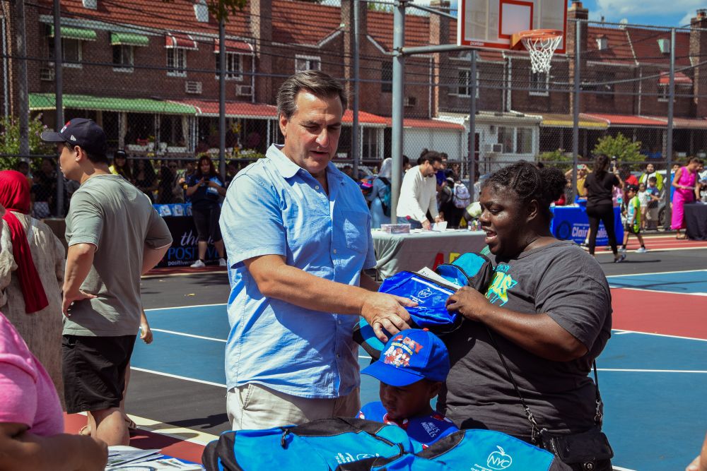 Senator Gianaris distributes backpacks and lunch boxes to families at PS 151