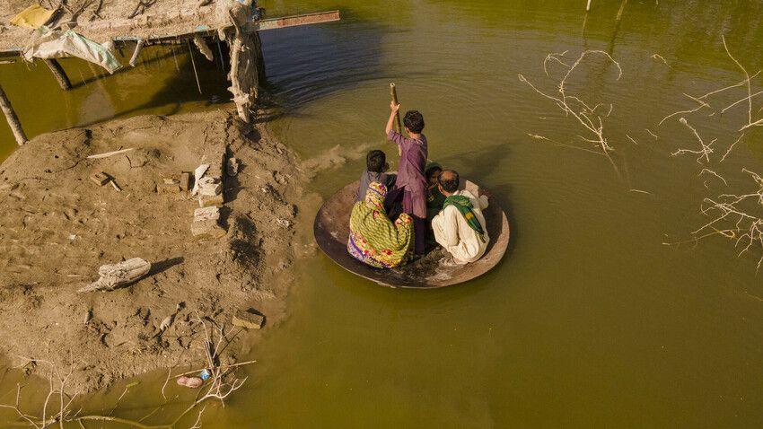 Aqib Aliin (14) transports people on his curry frying pan across the flooded waters in Jhuddo town of District Mirpurkhas of Sindh, Pakistan, following the devastating floods in 2022. Photo: Emmanuel Guddo/Concern Worldwide