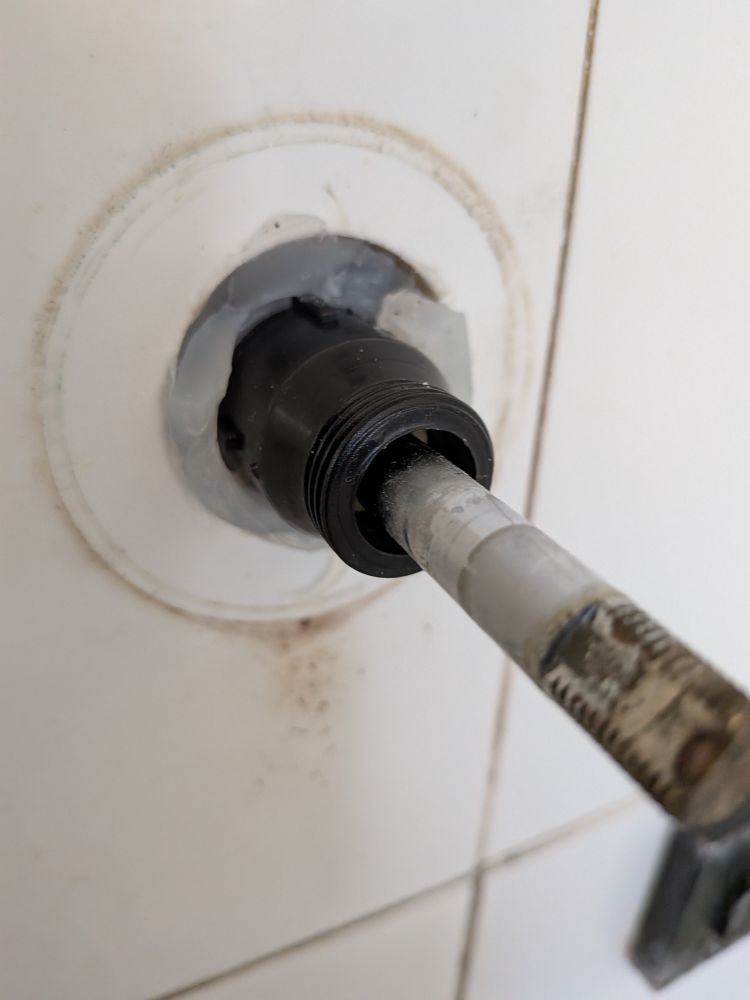 A close up of a tap spindle in a shower where some dumbfuck has put about 2 tubes of silicon sealant in the hole.