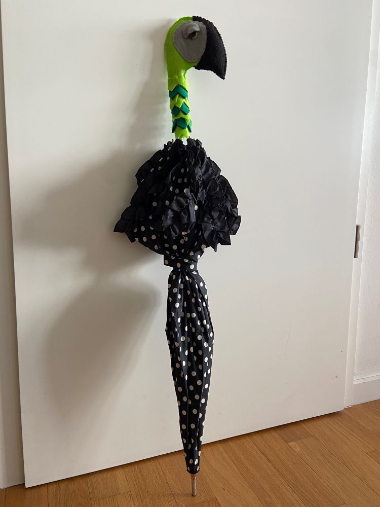 Old umbrella with a parrot head made out of felt.