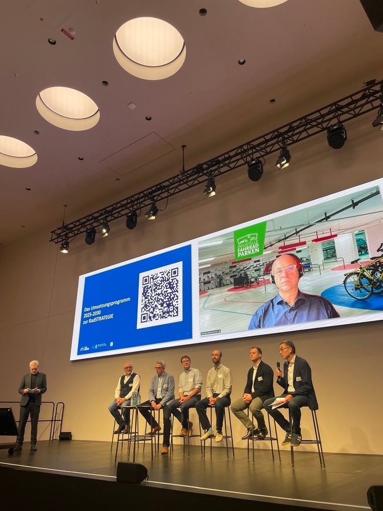 Moderator, sieben Teilnehmer auf der Bühne sind alle männlich.