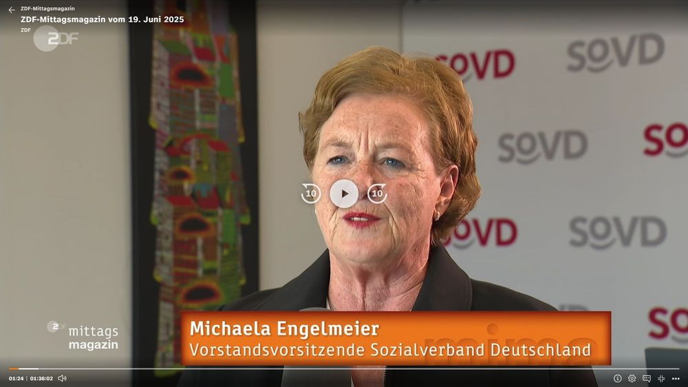 Screenshot aus dem ZDF-Mittagsmagazin vom 19. Juni 2025. Im Bild ist Michaela Engelmeier, die SoVD-Vorstandsvorsitzende, in einem Interview zu sehen. Sie steht vor einem Roll-up mit mehrfach erkennbarem SoVD-Logo in Grau und Rot. Sie trägt eine schwarze Jacke, hat kurzes, hellbraunes Haar und roten Lippenstift. Im linken Bildhintergrund ist ein farbenfrohes, abstrakt gestaltetes Wandbild zu erkennen. Am unteren Bildrand erscheint eine Bauchbinde in Orange mit ihrem Namen und Titel. Das Video ist bei Minute 1:24 angehalten. Es handelt sich um einen Screenshot aus einem Fernsehbeitrag mit eingeblendeten Senderlogos und Steuerungsbuttons.