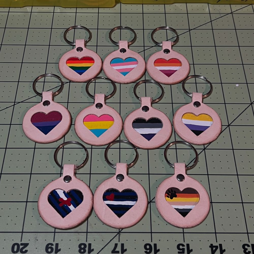 hand painted pride heart cutout leather keychains.  Available flags are in order Rainbow, Trans, Lesbian, Bi, Pan, Ace, Nonbinary, Pup, Leather & Bear! 
