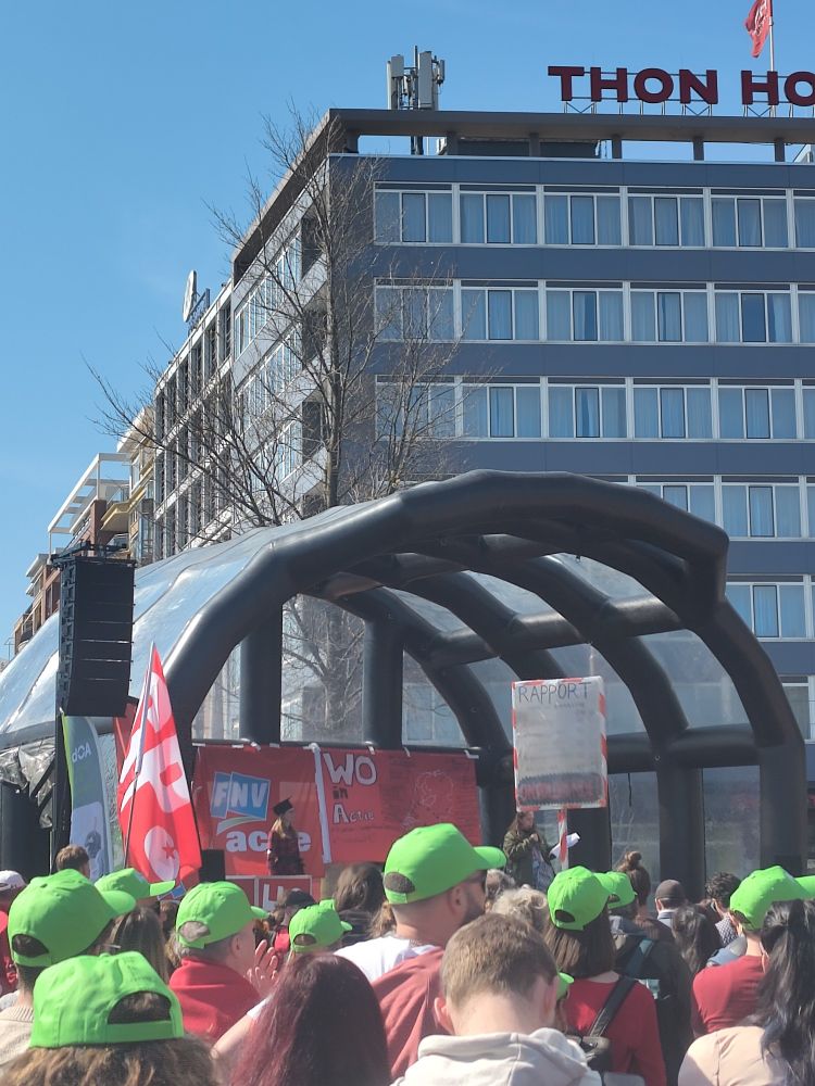 Group of people in front of a stage, at a protest against budget cuts in education 