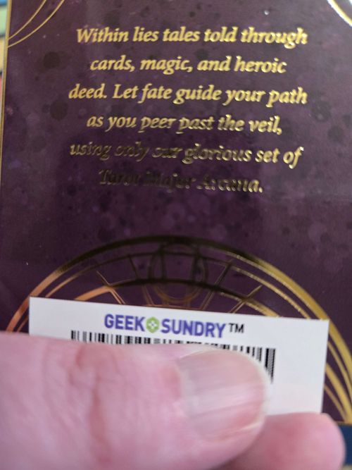 back of CR tarot deck box. gold text reads "Within lies tales told through cards, magic, and heroic deed. Let fate guide your path as you peer past the veil, using only our glorious set of [???] Major Arcana"

OP's thumb is highlighting the barcode, which bears the Geek & Sundry logo