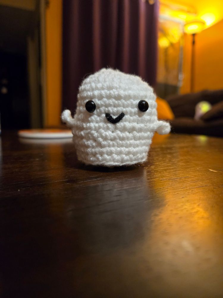 Tiny amigurumi ghost smiling at you