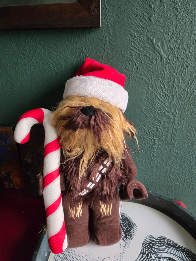 Chewbaca lego plushie in a Santa hat holding a candy cane almost as tall as he is.