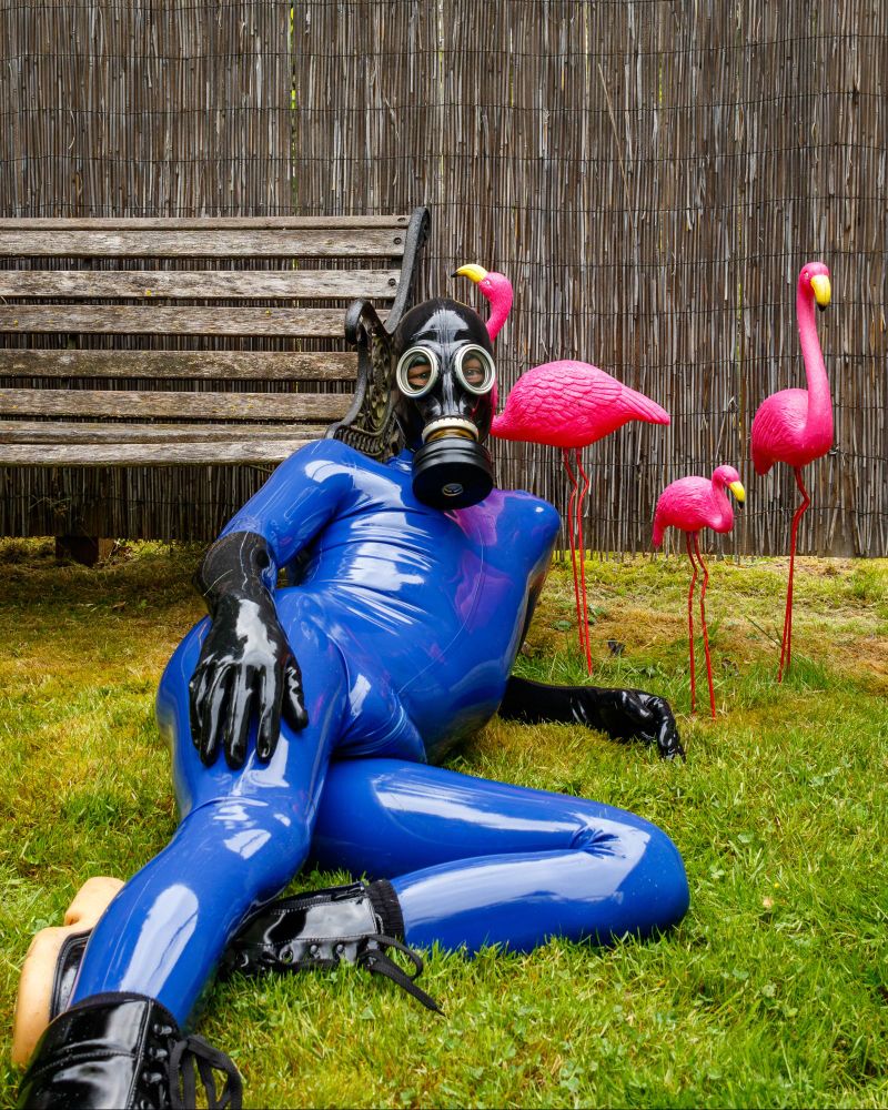 Lounging on the lawn in a blue catsuit with a gasmask. 