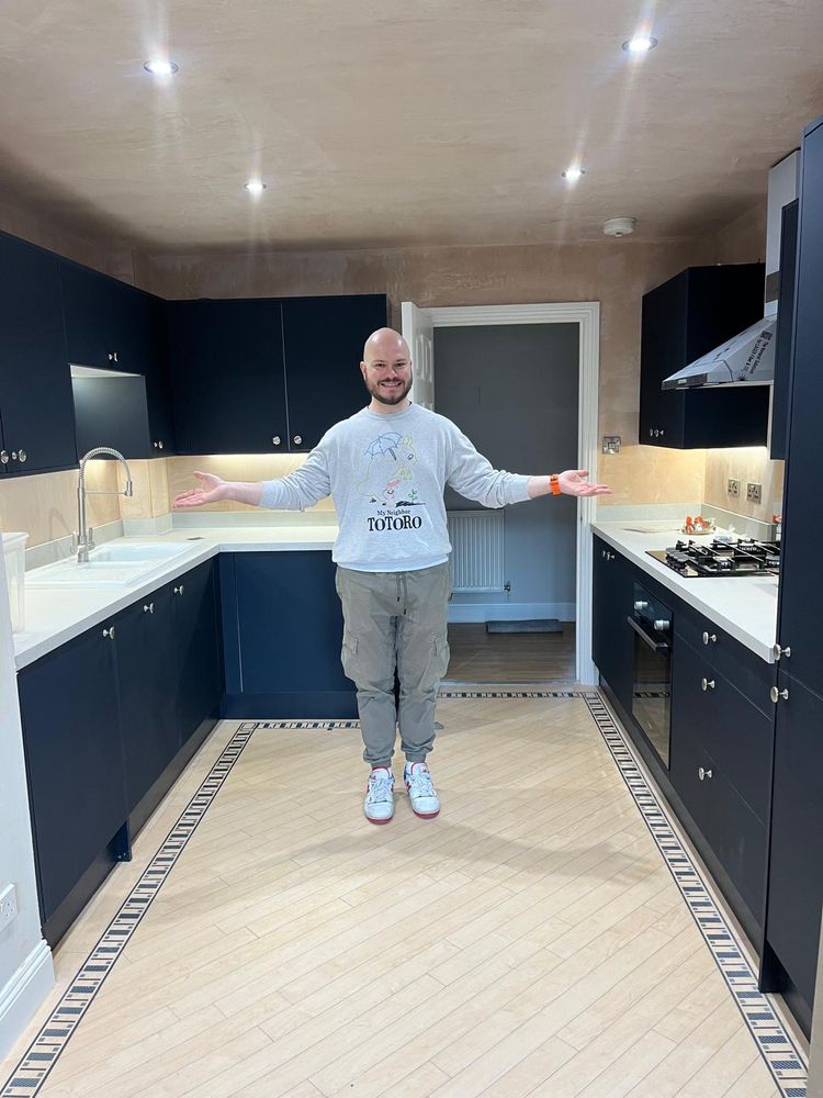 I'm standing in the middle of my new kitchen, positively beaming. The cabinets are a navy colour with white countertops.
