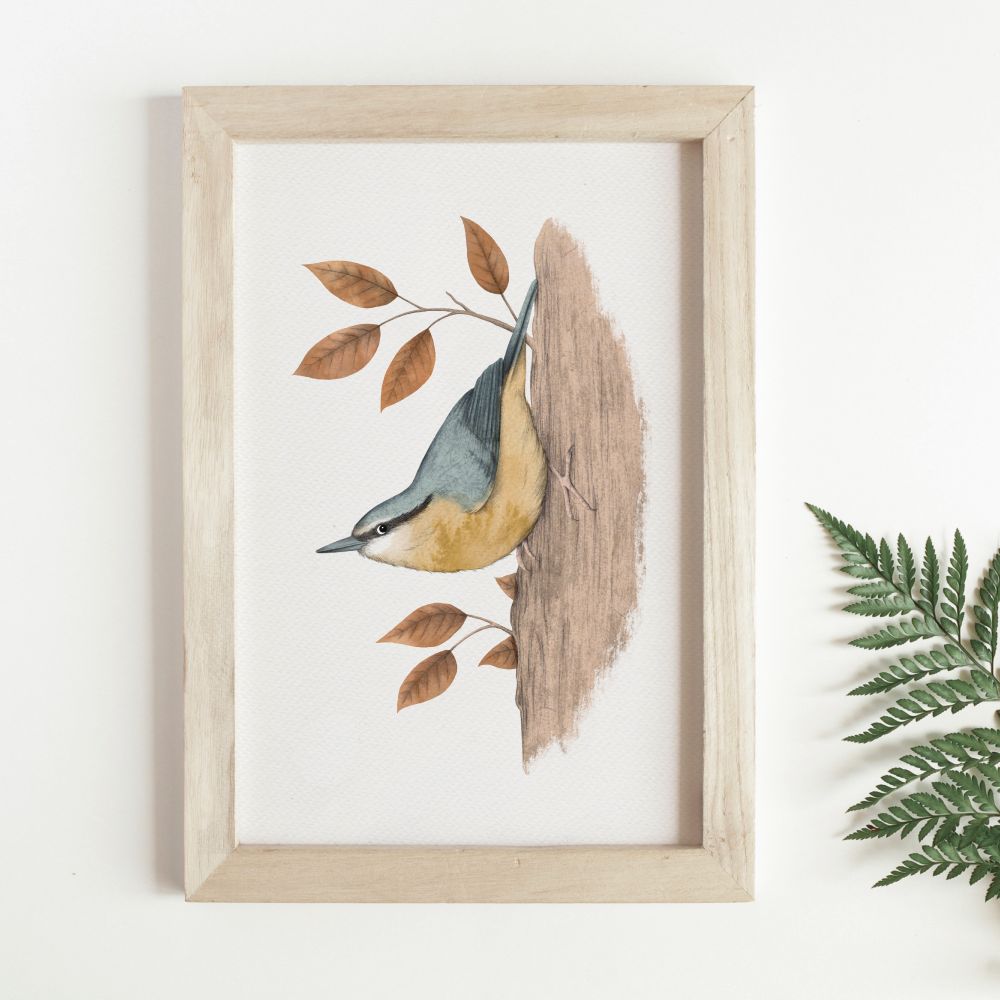 A wooden frame next to a Ferm leaf. In the frame is an illustration of a bee and yellow nuthatch bird with brown leaves on a white background. 