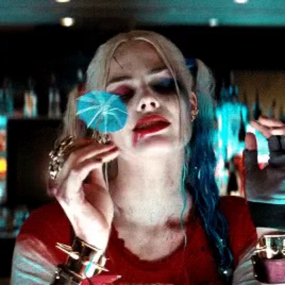 harley quinn from suicide squad is holding a blue umbrella in front of her face