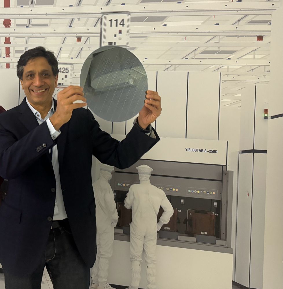holding a shiny round silicon wafer