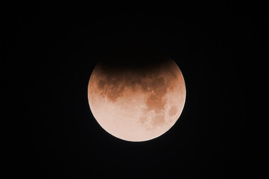 The full moon during a Lunar eclipse. The show of the Earth covers the top of the image. 