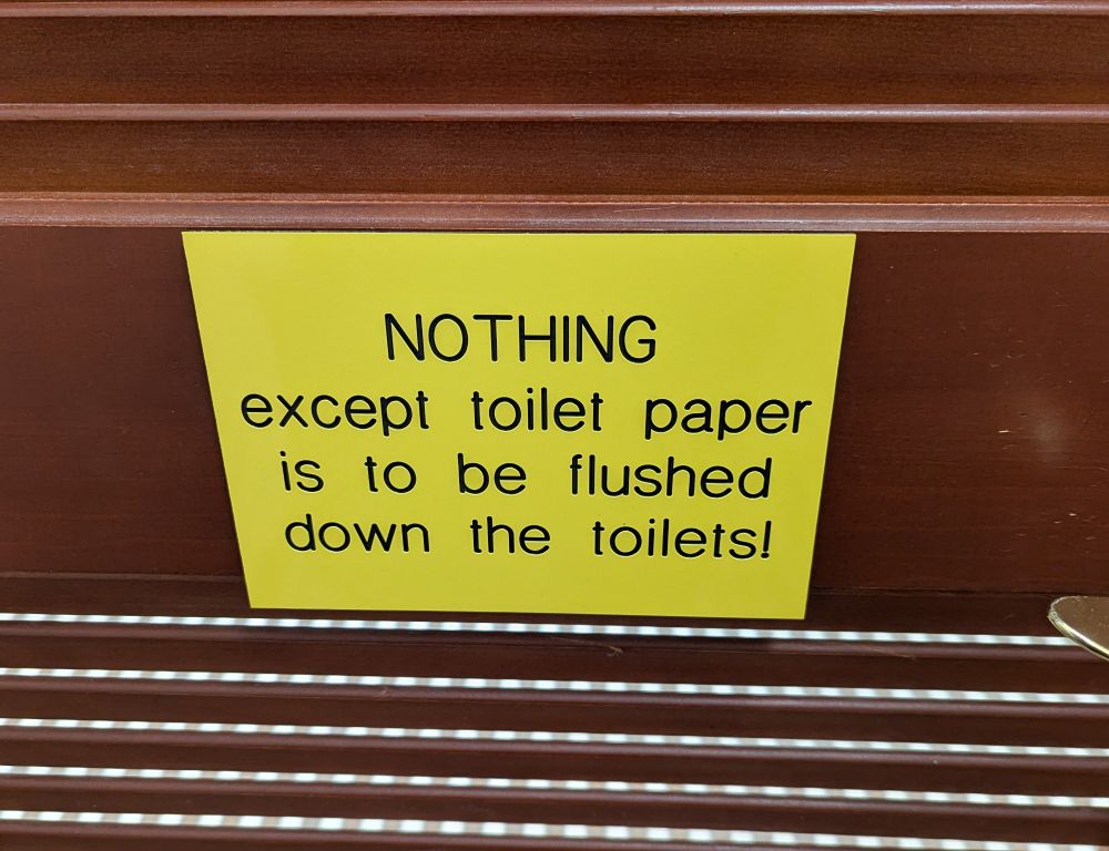 Bathroom door with a sign that says "NOTHING except toilet paper is to be flushed down the toilets!"