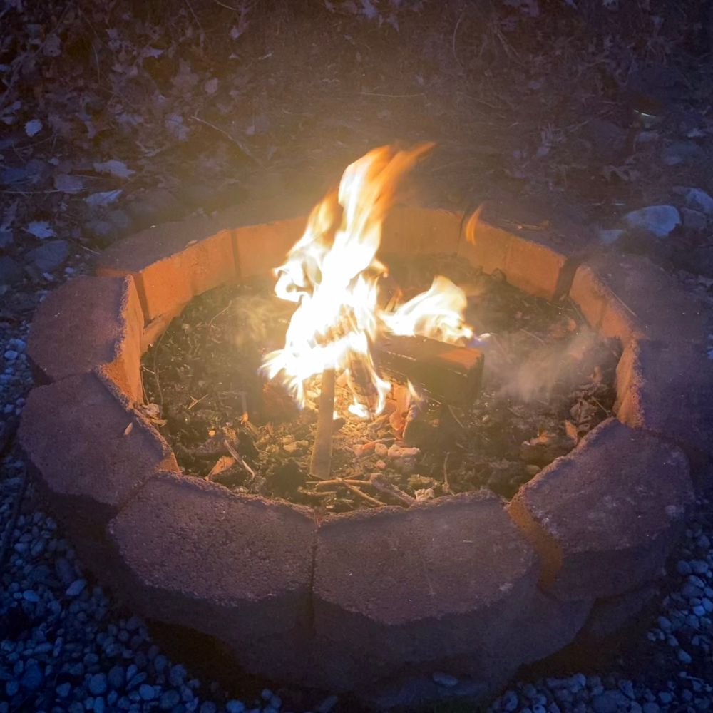 A small campfire is burning inside a ring of bricks. 
