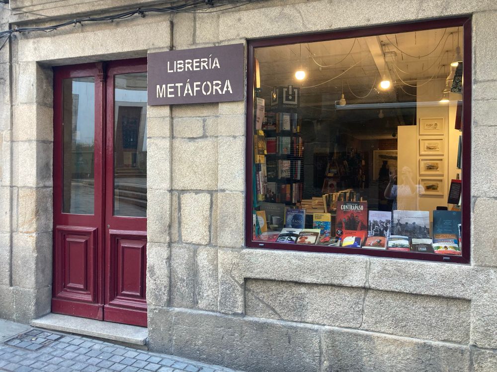 A small bookstore with red French door and a square window. Cobblestone street.