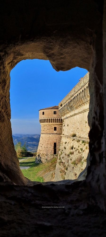 La fortezza d San Leo (Rimini) fotografata da una feritoia posta  nei camminamenti di guardia all'interno del torrione maggiore. Si intravvede la mura merlata e il torrione minore posto a nord della fortezza.