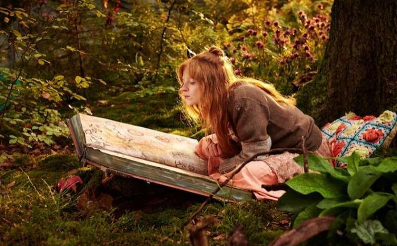 Bild zeigt Filmausschnitt aus dem Film "Die kleine Hexe" (2018)

Eine Frau mit rötlichen Haaren sitzt im Wald über einem riesigen Buch.