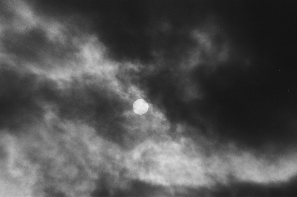 B&w photo of the Sun looking like a clear white circle in an cloudy day