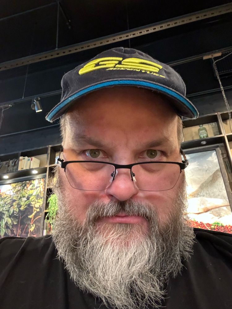 Keski-ikäinen mies, eli minä, katsoo lasien yli hieman ärsyyntynyt ilme kasvoillaan.