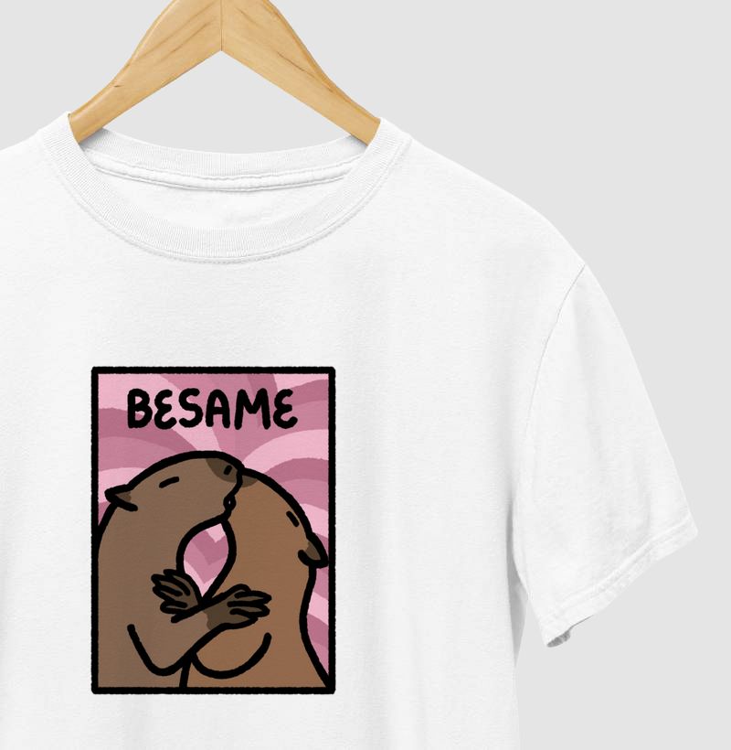 foto com zoom de camiseta branca com estampa de duas capivaras se beijando sobre um fundo rosado. acompanha o texto "besame"