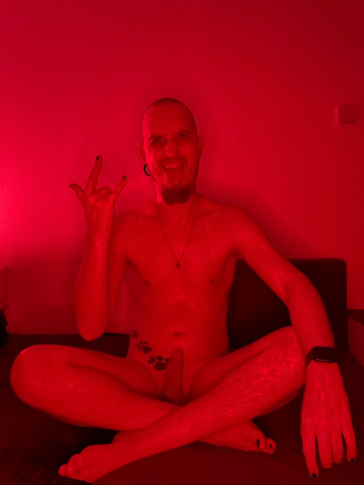 Naked man with devil’s horns on hand in red light and full erection