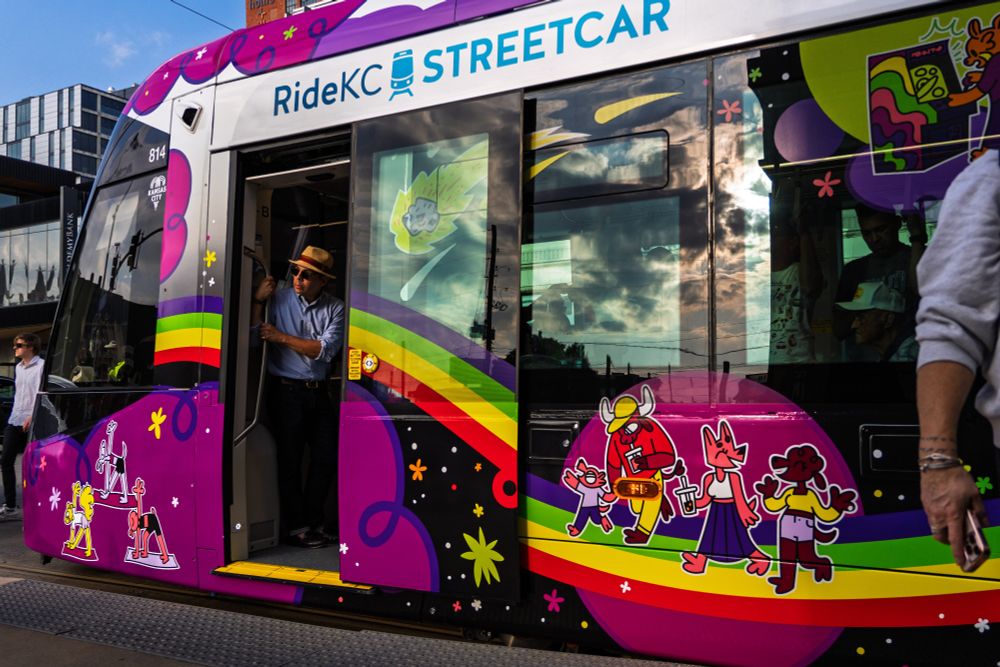 Man looking out of the open doors of a street car.