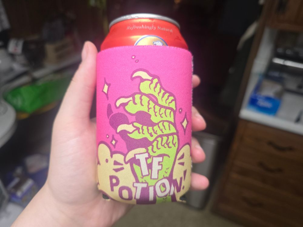 a mostly pink can coozie that says tf potion with a scaly hand reaching up
