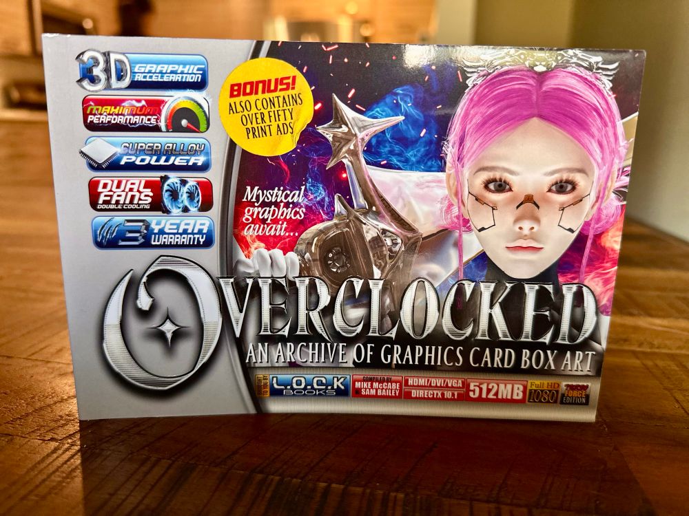 A book called Overclocked: An Archive of Graphic Card Box Art sitting on a wooden table 