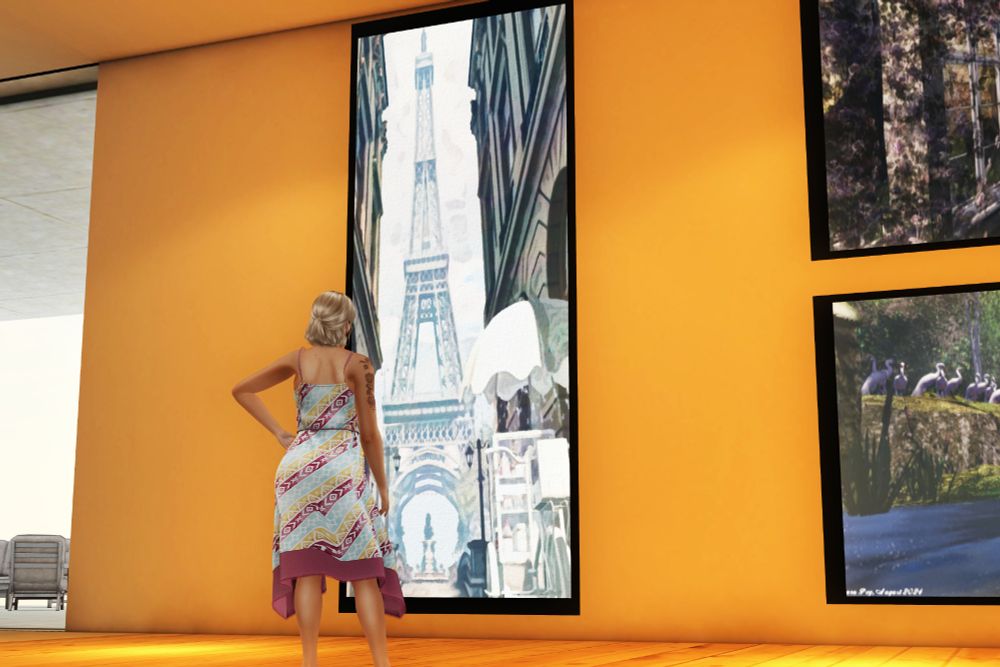A woman in a sundress stands in an art gallery looking at a large mounted image of the Eiffel Tower.