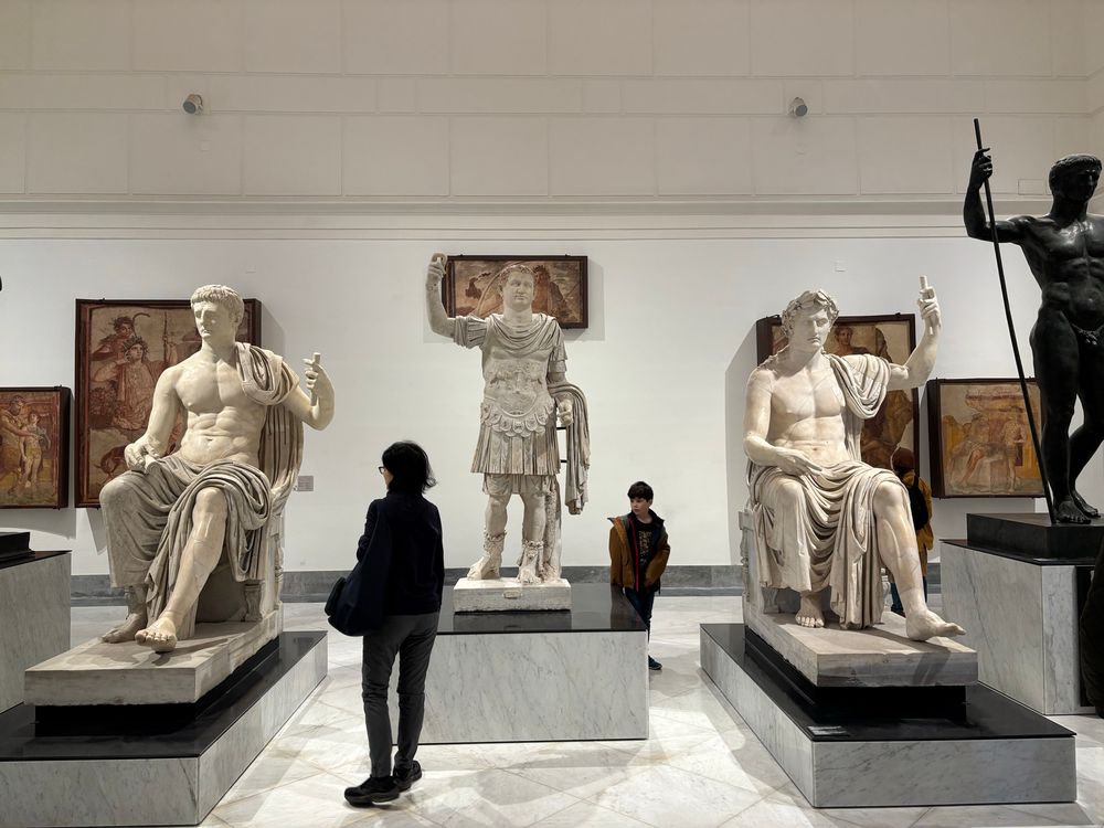 Three marble statues all holding their hands up to their faces 