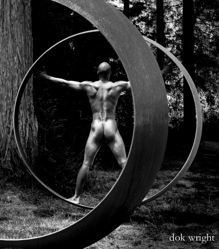 Male figure in a wooded sculpture garden. 