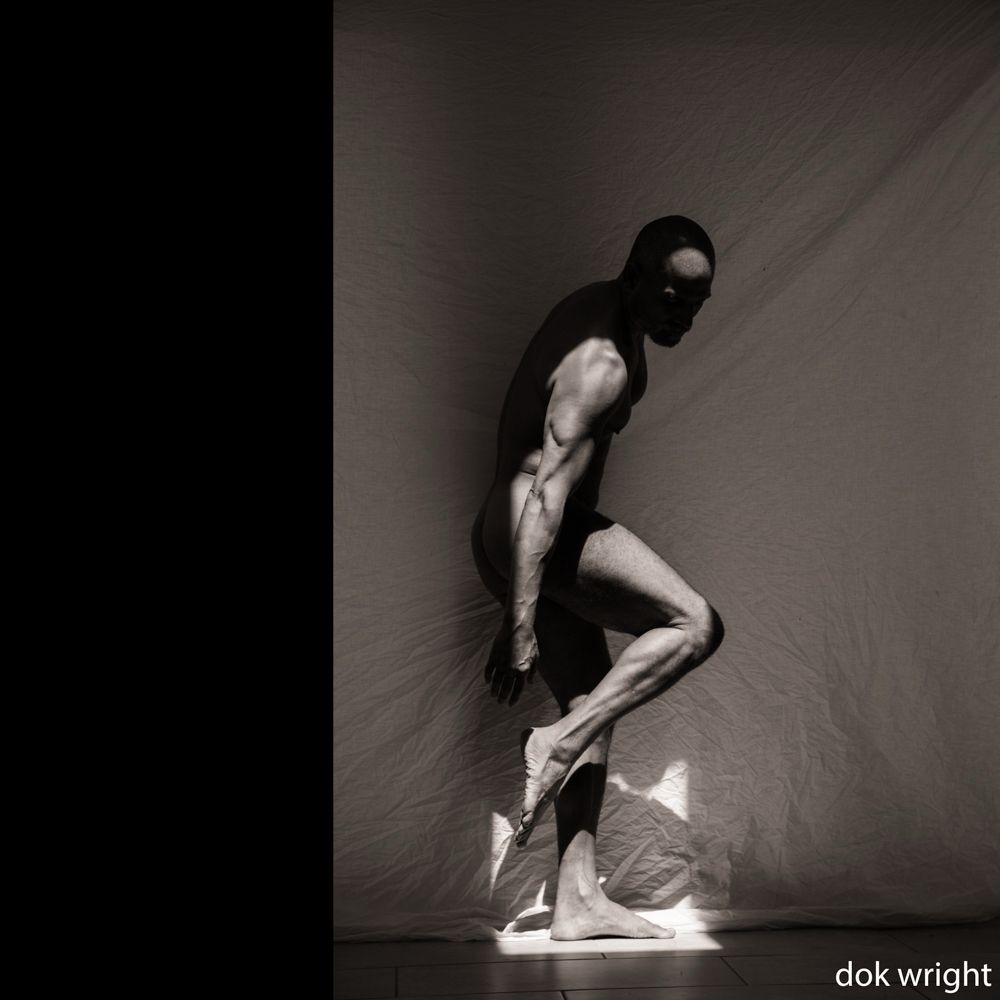 Male figure in sunlight from above. Against a white cloth background. 