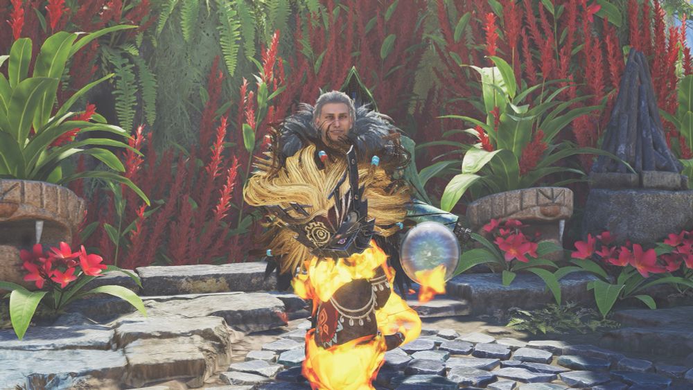 A "Monster Hunter Wilds" character based off of (specifically the 2018-2019 nat'l tour version of) Javert "Les Misérables" crouching slightly and smiling whilst his Palico—a brown cat with blue eyes wearing a fluffy helmet and fiery body armor—stands in front of him. They're in the Grand Hub adorned with the summer festival/Flamefete flowers, and Javert has a green Artian Bow on his back.