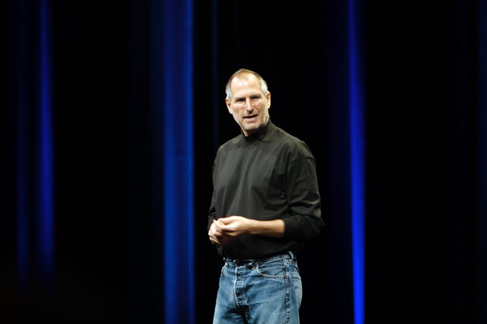 Steve Jobs wearing a black shirt and blue jeans standing on stage during a Keynote address in 2007. 
